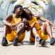 2 women in yellow tank top and black shorts sitting on white bench during daytime